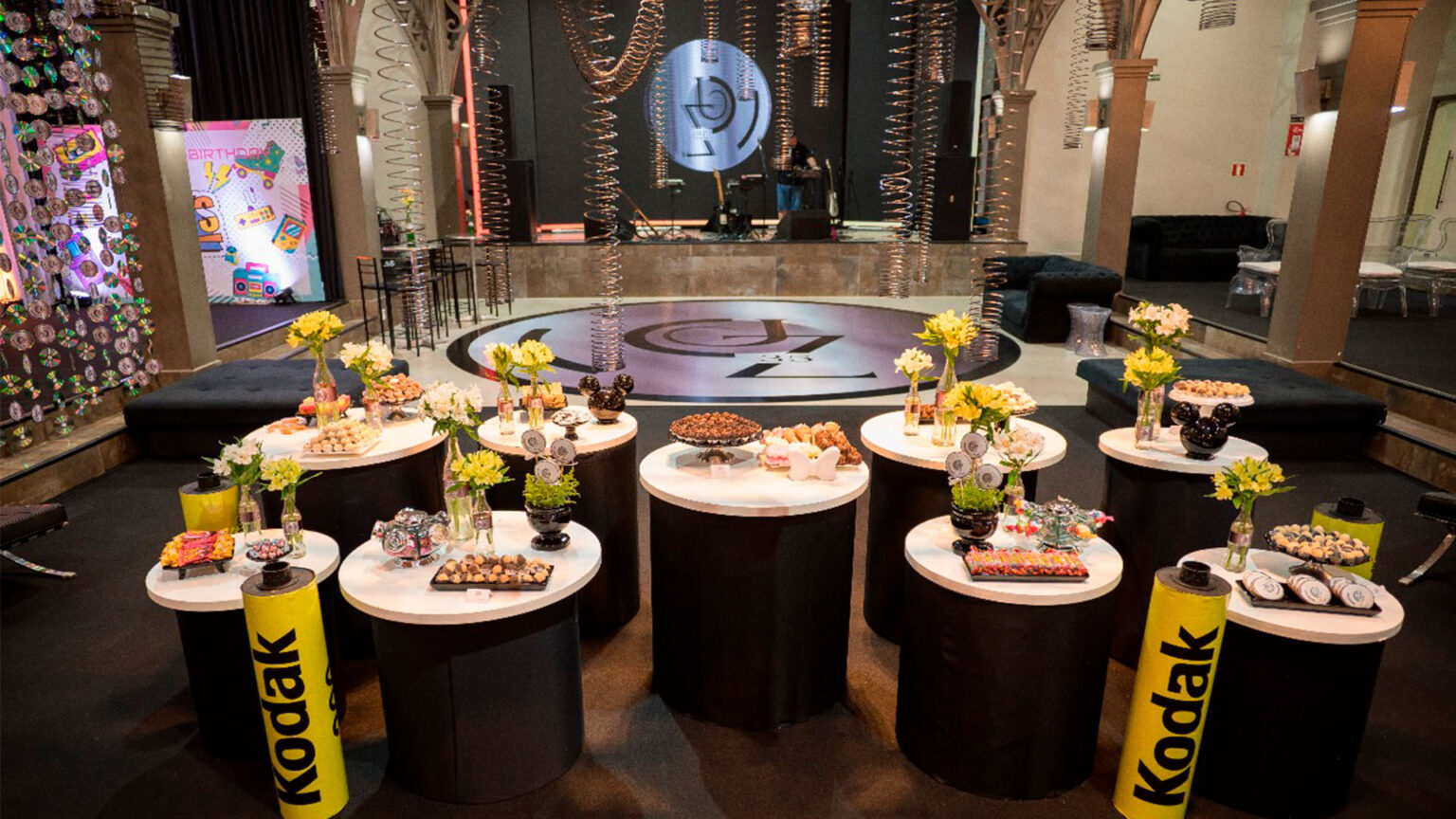 Festa temática: Dicas para criar momentos incríveis decoração festa temática anos 90 com elementos que remetem a Kodac, doces da epoca como paçocas, e ao fundo uma pista com discos pendurados