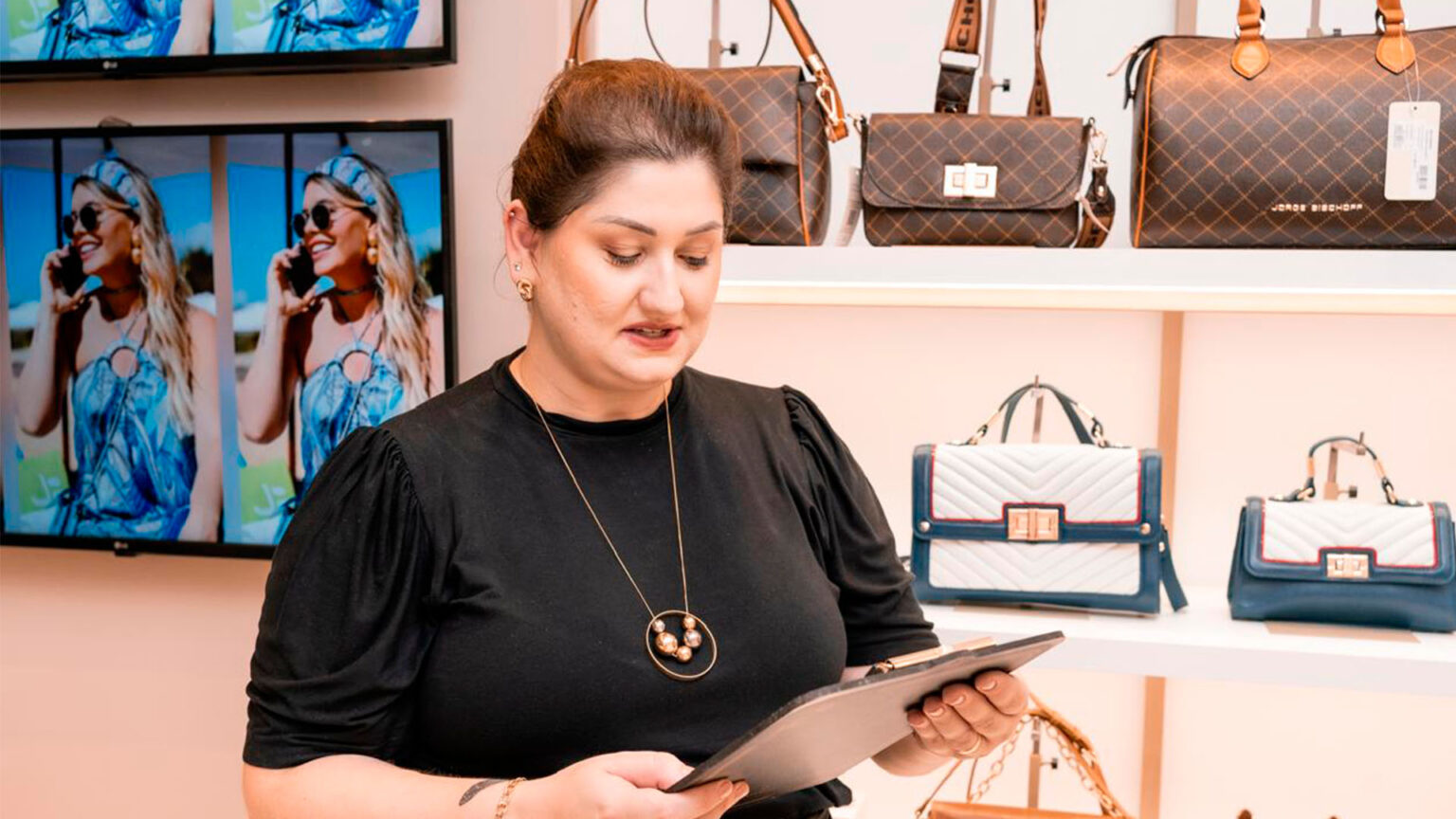 Transforme sua empresa de eventos com parcerias estratégicas jéssica zucco vestindo uma camisa preta, com cabelos castanhos em coque. Nas suas mãos segura uma prancheta enquanto orienta uma empresa de eventos para melhores ações para seu crescimento.